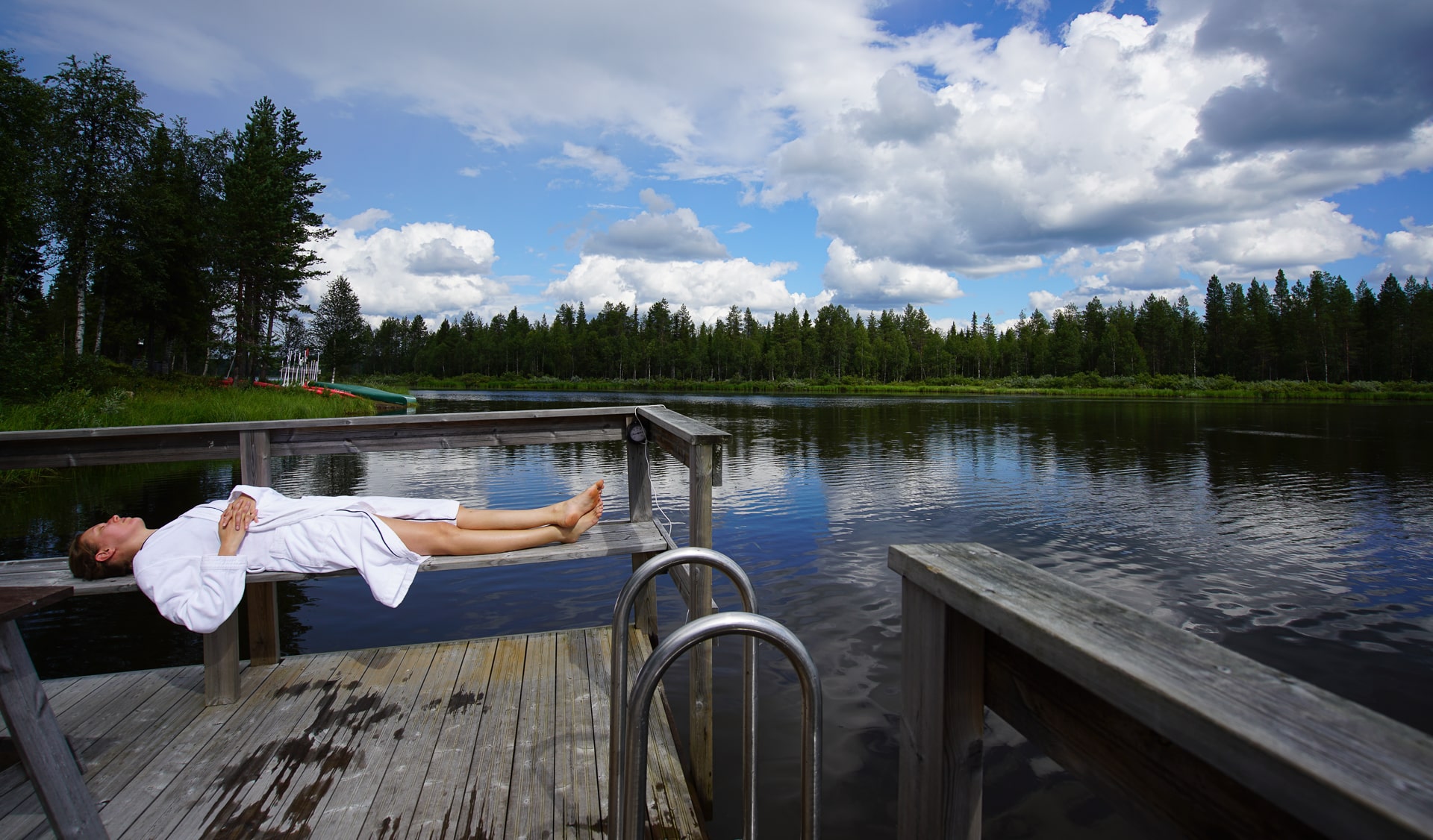 Mann im Bademantel liegt auf Bank am See © Tarja Prüss